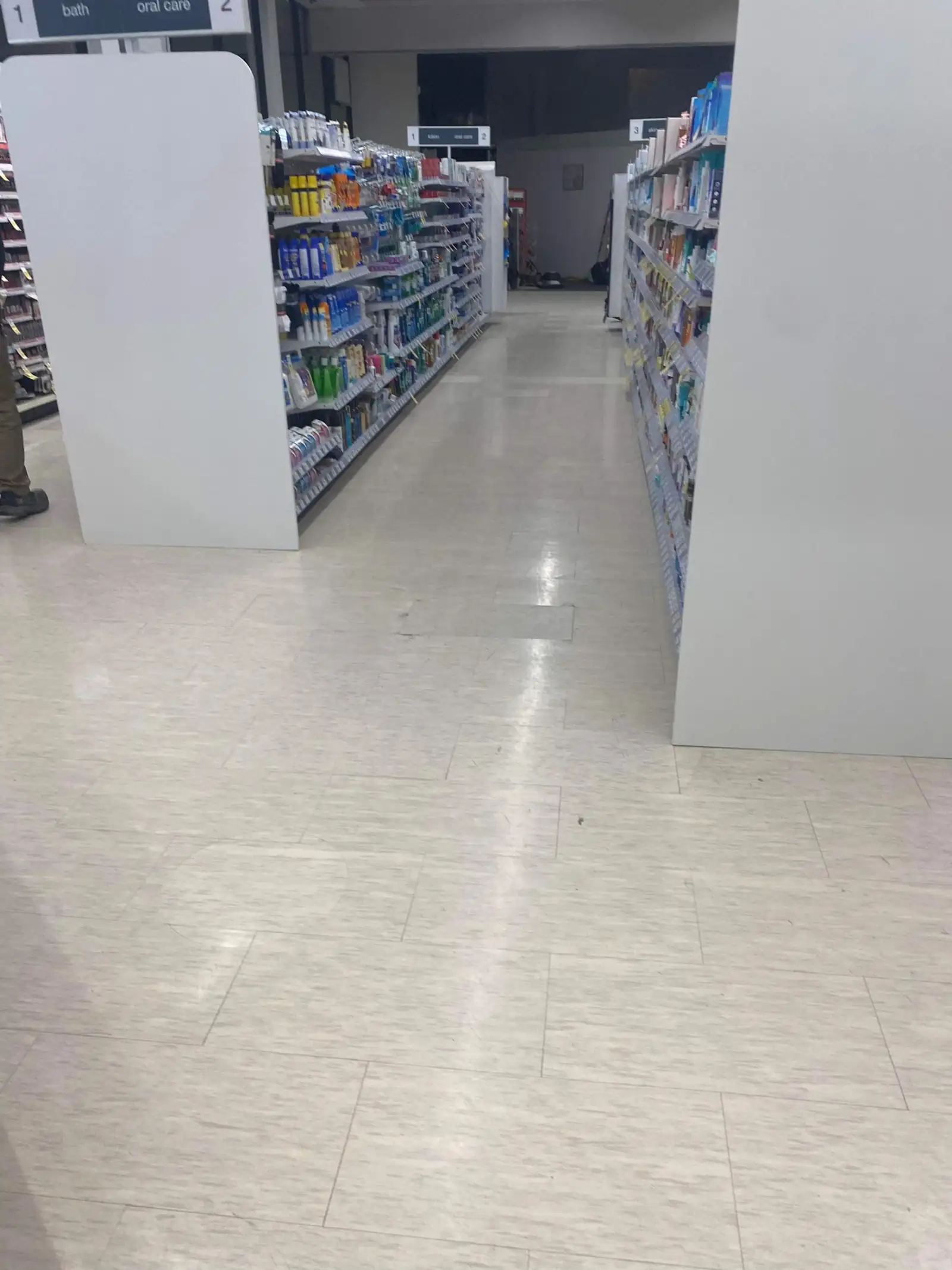 Buffed retail pharmacy aisle flooring reflecting overhead lighting